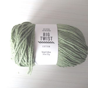 Könnte beinhalten: Ein Knäuel Salbeigrün Big Twist Cotton Garn. Das Etikett lautet "85% Baumwolle, 15% Polyester, BIG TWIST COTTON, 132 m / 75 g."