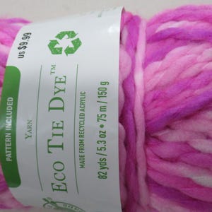 Op de afbeelding: Een bol roze, wit en paars garen met het label "ECO TIE DYE" gemaakt van gerecycled acryl. Het garen is 82 yards / 5,3 ounce of 75 meter / 150 gram. De prijs is $ 9,99.