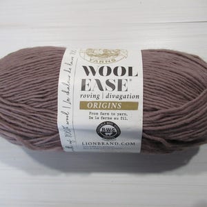 Puede incluir: Un ovillo de lana roving Wool-Ease de Lion Brand en color malva apagado. La etiqueta dice "Wool Ease" y "Origins". La lana está hecha de 100% lana. La etiqueta también incluye el texto "From farm to yarn" y "De la ferme au fil."