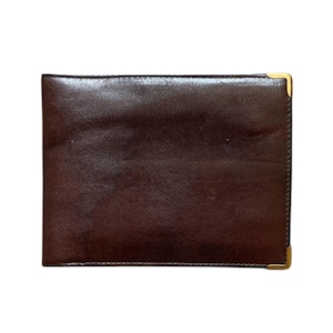 Może przedstawiać: Prostokątny, ciemnobrązowy skórzany portfel ze złotymi narożnikami. Portfel ma gładką, wypolerowaną powierzchnię i wydaje się być zamknięty. Design jest prosty i klasyczny, odpowiedni do codziennego użytku.