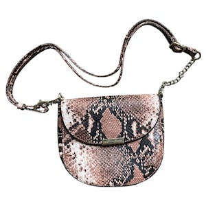 May include: A crossbody bag with a snakeskin pattern in shades of brown, black, and white. The bag has a curved shape with a flap closure and a silver-tone chain strap. The adjustable strap is brown.