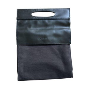 May include: Black leather clutch bag with a rectangular shape and a handle. The top flap has a cutout handle and the brand name "GIVENCHY" embossed. The bottom is a dark fabric pouch.