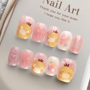 May include: A set of ten press-on nails featuring a light pink base with yellow cartoon duck characters, glitter, stars, hearts, and plaid patterns. The display card reads Nail Art, Thank you for your order. I hope you like it.