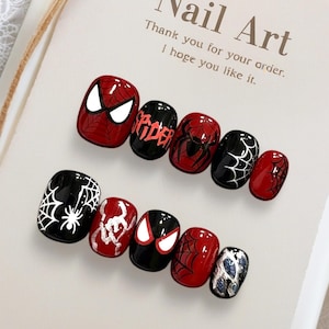 Könnte beinhalten: Ein Set aus zehn Press-on-Nägeln in Rot und Schwarz mit Spider-Man-Motiven, darunter Spinnennetze, Augenmotive und der Schriftzug 'SPIDER'. Die Nägel sind auf einer Karte mit dem Text 'Nail Art Thank you for your order. I hope you like it.' befestigt.