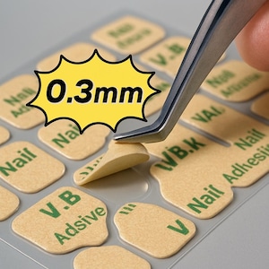 May include: Image of nail adhesive pads being peeled with tweezers. The pads are beige with green text, and the image includes text that says "Ultra-thin, safe for hands & easy to peel" and "0.3mm".