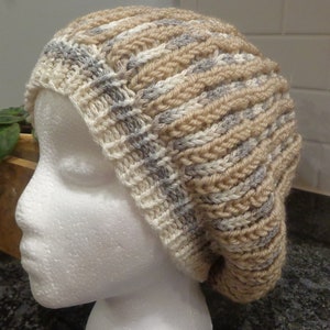 May include: A beige and gray knitted slouchy beanie hat with a ribbed texture.