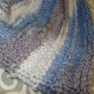 May include: A close-up of a knitted fabric with stripes of blue, gray, and white.