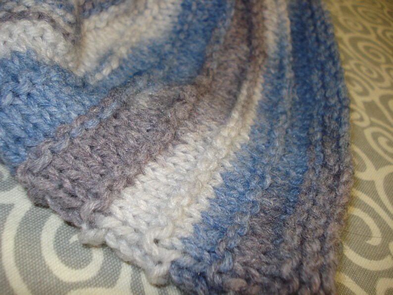 May include: A close-up of a knitted fabric with stripes of blue, gray, and white.