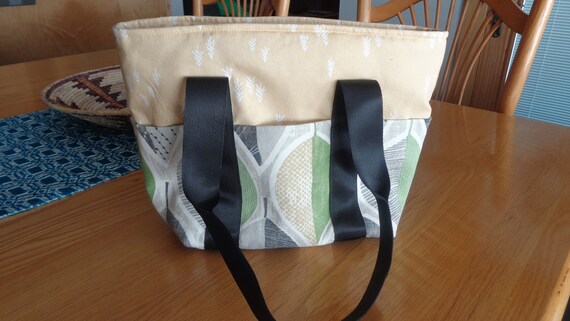 Zippered purse/ tote, padded with outside pockets, lining and black webbing straps.