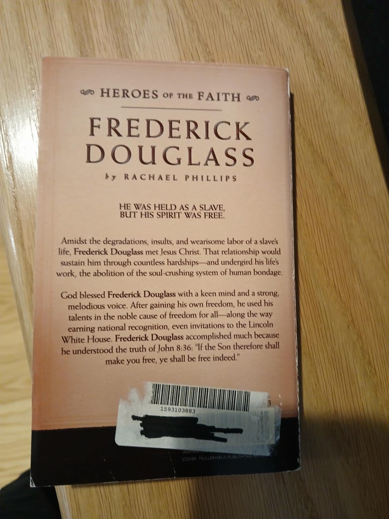 May include: A book titled "Frederick Douglass" by Rachael Phillips, part of the "Heroes of the Faith" series. The cover is a light tan color with black text. The book's description includes the quote, "He was held as a slave, but his spirit was free."