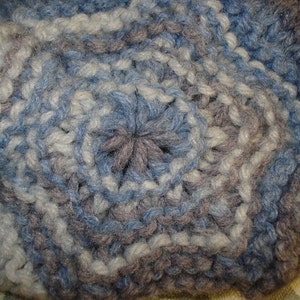 May include: Close-up of a crocheted fabric with a blue, white, and gray color pattern.