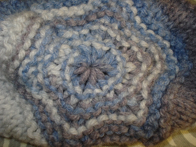 May include: Close-up of a crocheted fabric with a blue, white, and gray color pattern.