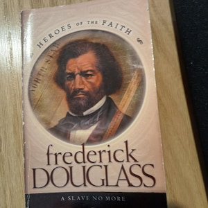 May include: A book titled "Frederick Douglass: A Slave No More" from the "Heroes of the Faith" series. The cover features a portrait of Frederick Douglass in a circular frame, with the words "North Star" around the frame.