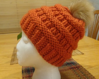 Hand knit bulky orange hat with fur pom pom.