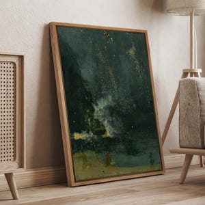 May include: Abstract art print in a wooden frame. The artwork features a dark green and gold color palette with brushstrokes and a textured appearance. The painting is leaning against a wall, showcasing a modern aesthetic.