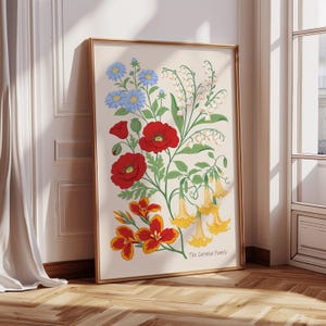 以下が含まれることがあります： 赤、黄、青、白の花が描かれた額入りの花の芸術プリント。ポピー、ユリ、その他の花が含まれており、下部には「The Carmina Family」の文字があります。フレームは金色です。