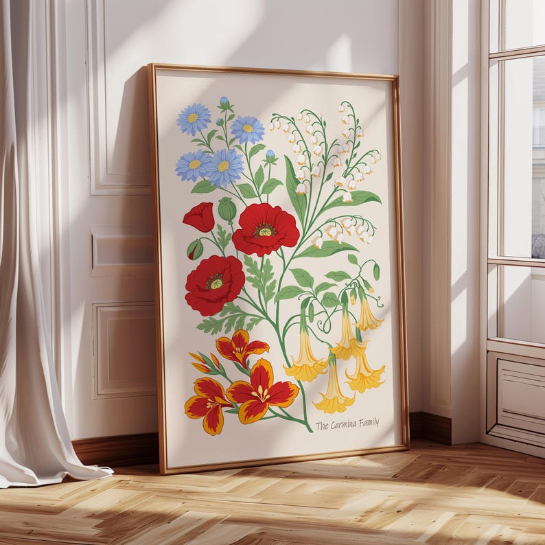 以下が含まれることがあります： 赤、黄、青、白の花が描かれた額入りの花の芸術プリント。ポピー、ユリ、その他の花が含まれており、下部には「The Carmina Family」の文字があります。フレームは金色です。