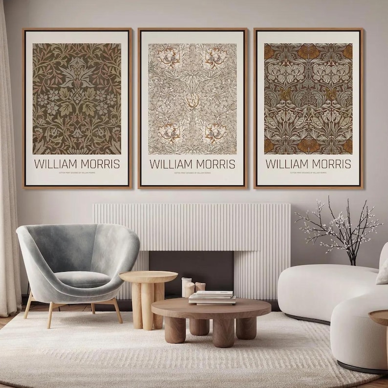 Puede incluir: Tres impresiones enmarcadas de patrones florales de William Morris en marr&oacute;n, beige y blanco. Las impresiones est&aacute;n colgadas en una pared con una chimenea blanca y un sill&oacute;n gris en primer plano.