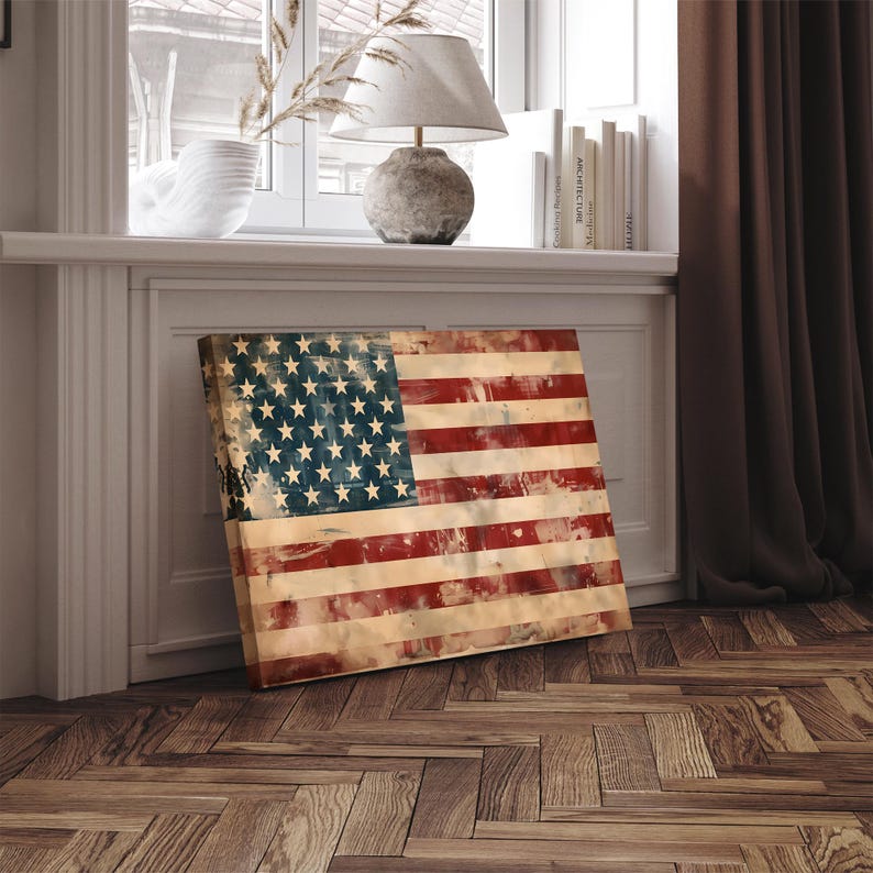 May include: A rectangular canvas print of the American flag, featuring a distressed, vintage design. The flag displays red and white stripes with a blue canton filled with white stars. The artwork is leaning against a white wall on a wooden floor.