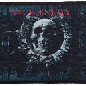Puede incluir: Un parche en blanco y negro con el nombre de la banda "ARCH ENEMY" en texto rojo. El parche presenta una calavera con un diseño detallado en el centro.