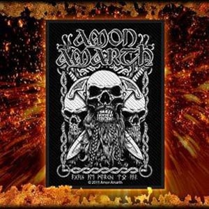 Puede incluir: Parche bordado en blanco y negro con el nombre de la banda "Amon Amarth" en una fuente estilizada. El parche presenta tres calaveras con espadas y un diseño de cadena. El texto "Evil In Person, To The End" está debajo de las calaveras. El símbolo de copyright y "2011 Amon Amarth" están debajo del texto.