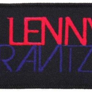 Puede incluir: Parche de tela negro con el texto "LENNY KRAVITZ" en letras rojas y azules.