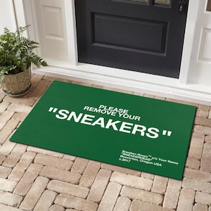 May include: Green doormat with white text that reads "Please remove your "SNEAKERS"". The text is in a bold, sans-serif font. The doormat is made of a durable material and is perfect for high-traffic areas.