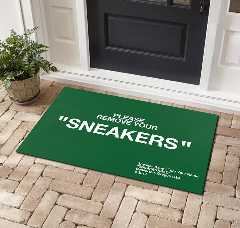May include: Green doormat with white text that reads "Please remove your "SNEAKERS"". The text is in a bold, sans-serif font. The doormat is made of a durable material and is perfect for high-traffic areas.