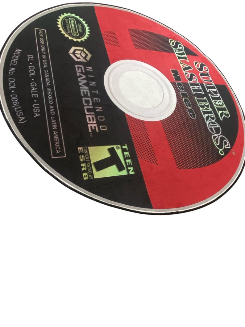 May include: A red and black GameCube disc with the text "SUPER SMASH BROS. Melee" and "NINTENDO GAMECUBE" printed on it. The disc is rated "T" for Teen by the ESRB.