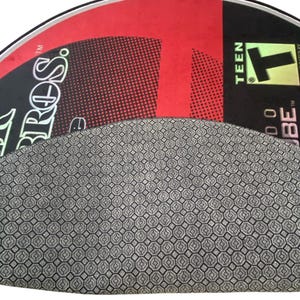 May include: A red and black half-circle shaped inflatable tube with the text "TUBE" and "TEEN" printed on it. The tube has a black and white geometric pattern on the bottom.