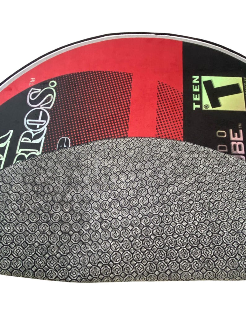 May include: A red and black half-circle shaped inflatable tube with the text "TUBE" and "TEEN" printed on it. The tube has a black and white geometric pattern on the bottom.