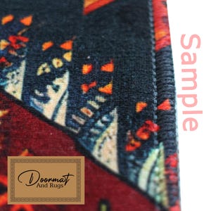 May include: A colourful doormat with a geometric pattern in shades of red, orange, blue, and white. The doormat has a black border and the text "Doormat And Rugs" is printed in a brown rectangle in the bottom left corner. The doormat is a sample.
