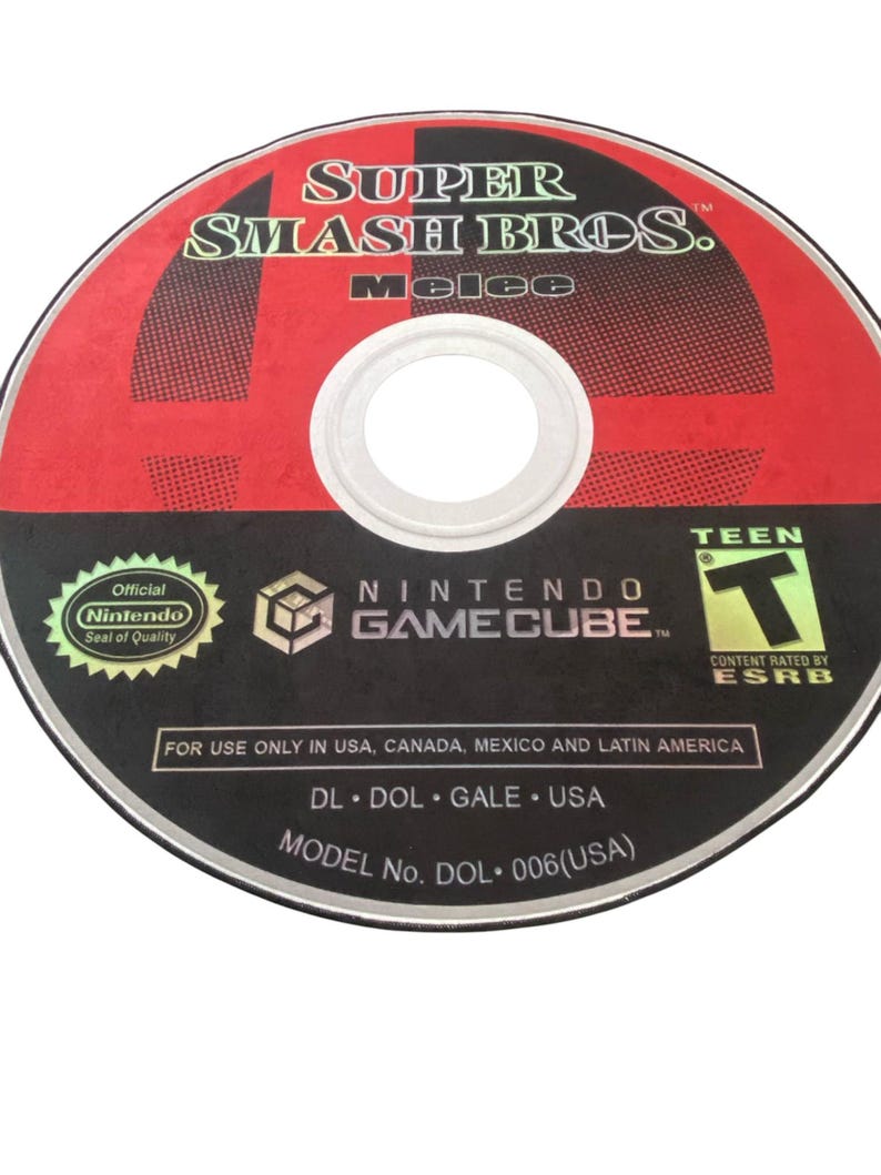 May include: A red and black Nintendo GameCube disc with the text "SUPER SMASH BROS. melee" and "NINTENDO GAMECUBE" printed on it. The disc also has a "TEEN" rating from the ESRB.