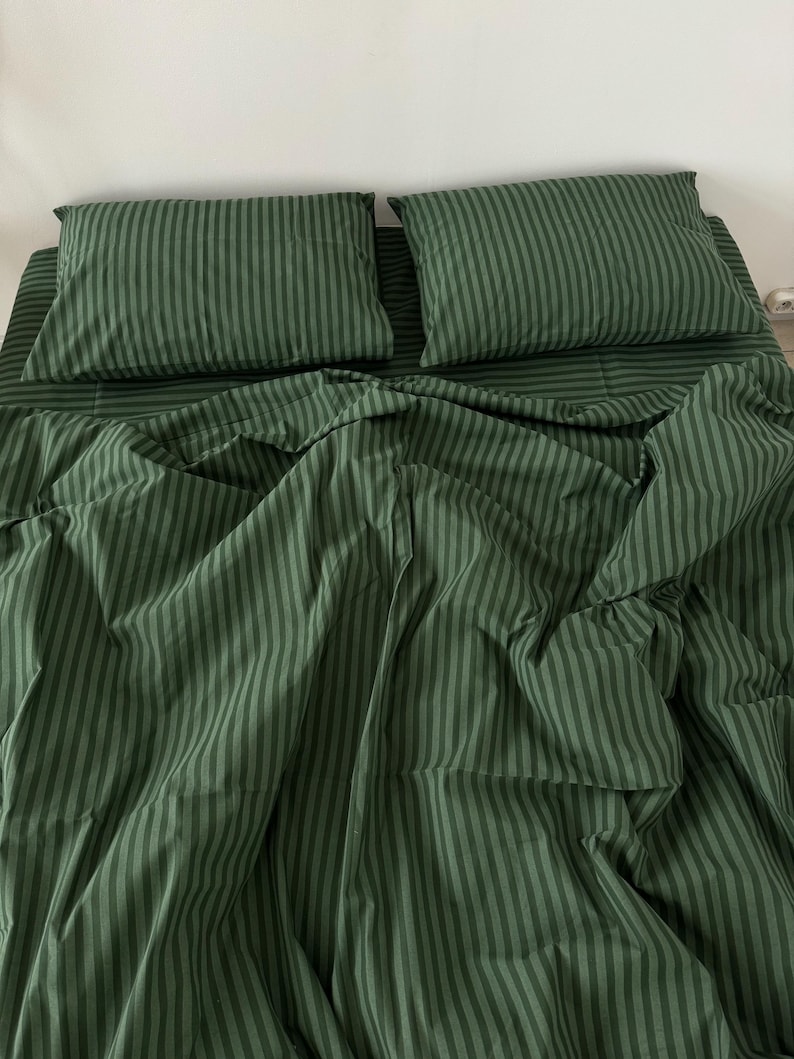 Puede incluir: Bedding rayado verde sobre fondo blanco. La ropa de cama est&aacute; hecha de una tela suave y c&oacute;moda, perfecta para un dormitorio.