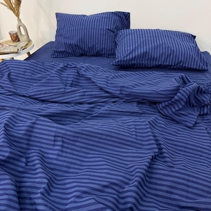 May include: A blue striped bedding set with two pillowcases. The bedding is made of soft, comfortable fabric and features a classic striped pattern.