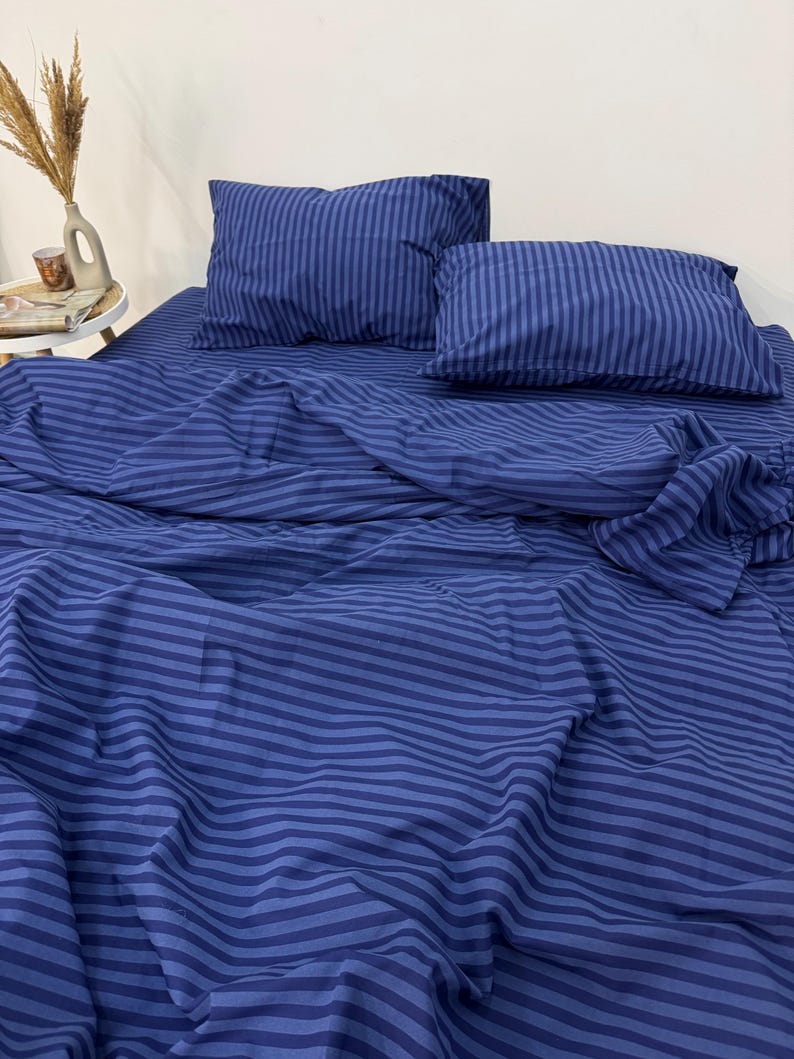 May include: A blue striped bedding set with two pillowcases. The bedding is made of soft, comfortable fabric and features a classic striped pattern.