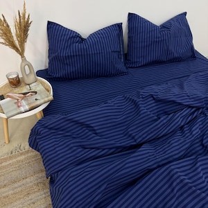 May include: A blue striped bedding set with a duvet cover and two pillowcases. The bedding is made of soft, comfortable fabric and features a classic striped pattern.