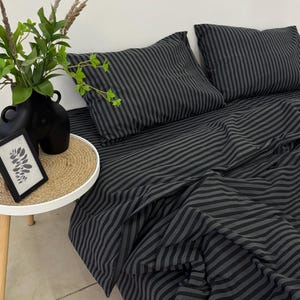 May include: Black and grey striped bedding with two matching pillowcases. The bedding is made of a soft, comfortable fabric and has a modern, minimalist design.