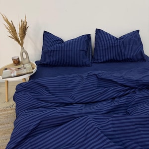 May include: A blue striped bedding set with two pillowcases. The bedding is made of a soft, comfortable fabric and features a classic striped pattern.