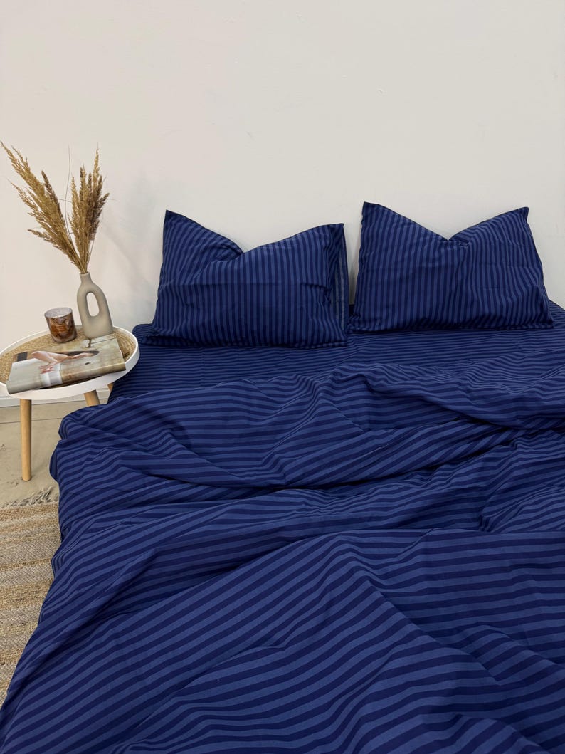 May include: A blue striped bedding set with two pillowcases. The bedding is made of a soft, comfortable fabric and features a classic striped pattern.