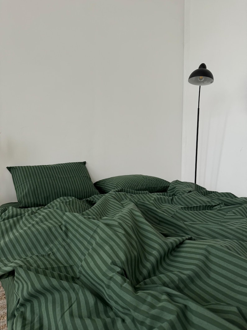 Puede incluir: Bedding de rayas verdes sobre fondo blanco. La ropa de cama est&aacute; hecha de tela suave y c&oacute;moda, perfecta para un dormitorio.