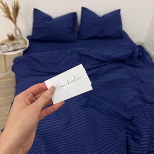 May include: Blue striped bedding with a white card that says "Home brand" on it.