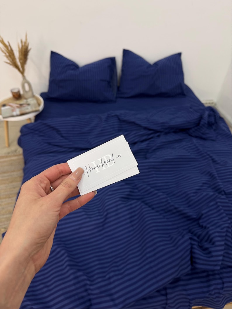 May include: Blue striped bedding with a white card that says "Home brand" on it.