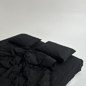 May include: A black bed with a black duvet cover and two black pillows. The bed is made and the sheets are smooth.