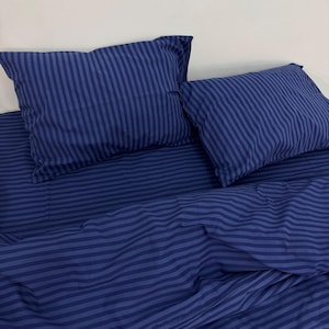 Peut inclure: Un ensemble de literie rayé bleu avec une housse de couette et deux taies d'oreiller. La literie est faite d'un tissu doux et confortable et présente un motif rayé classique.