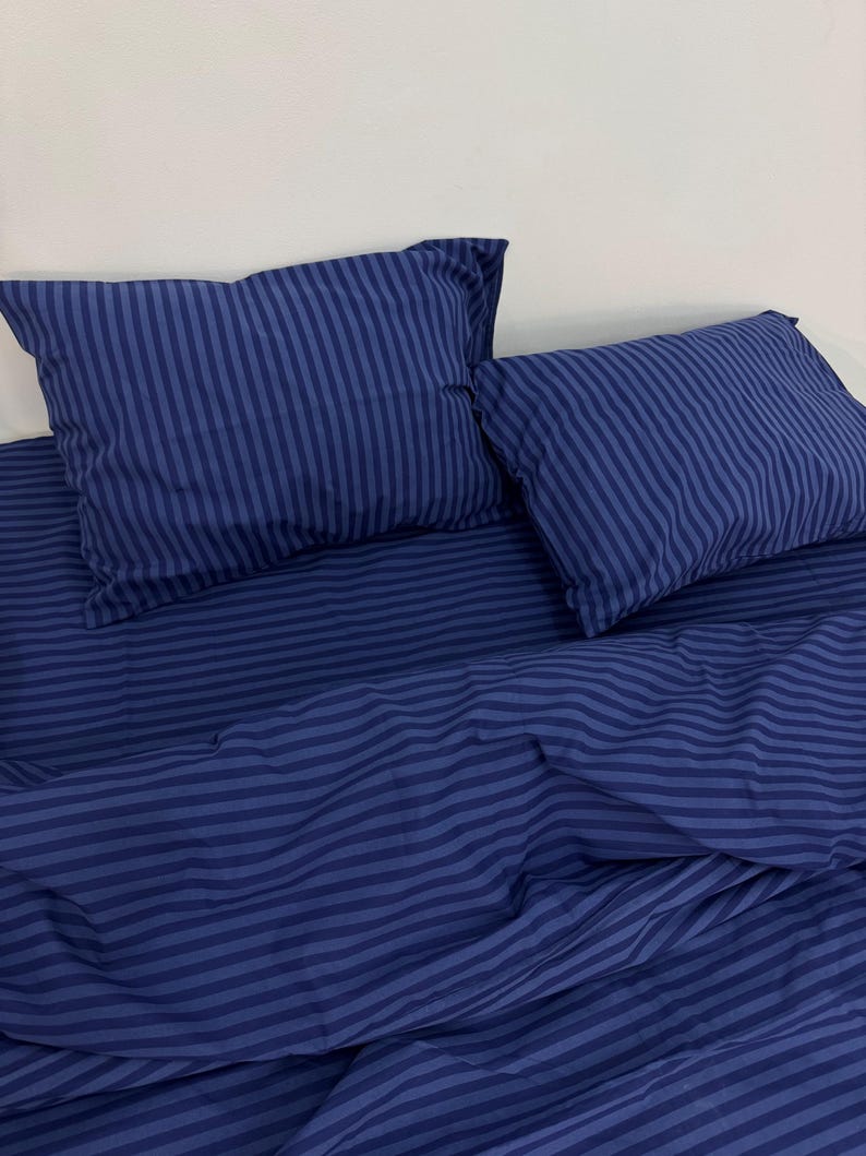 May include: A blue striped bedding set with a duvet cover and two pillowcases. The bedding is made of soft, comfortable fabric and features a classic striped pattern.