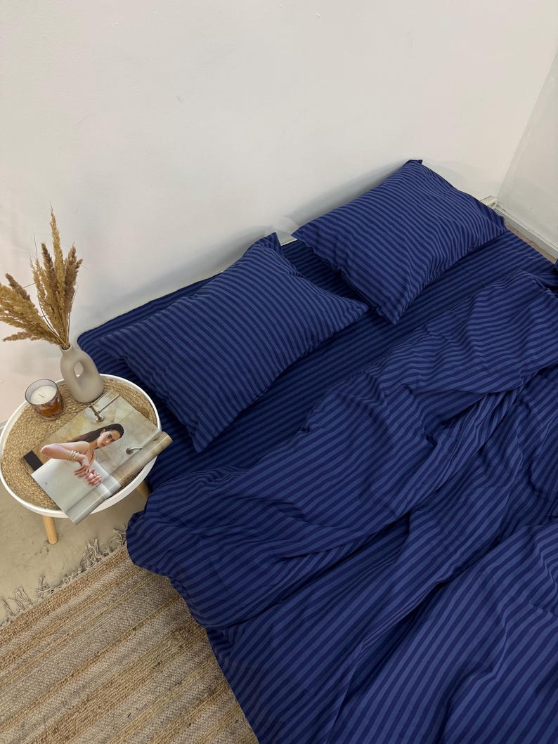 May include: A blue striped bedding set with a duvet cover and two pillowcases. The bedding is made of soft, comfortable fabric and features a classic striped pattern.