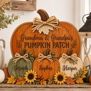 May include: A wooden pumpkin-shaped sign featuring the text Grandma & Grandpa's PUMPKIN PATCH, with three smaller pumpkins below labeled Joseph, Sophia, and Harper. The design includes raffia bows, sunflowers, and autumn-colored leaves.