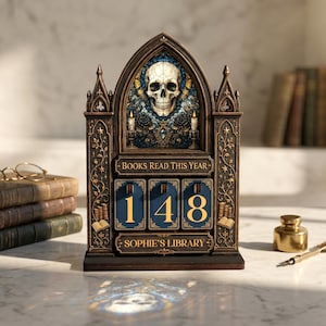 May include: A dark brown, gothic-style wooden book tracker with a pointed arch top featuring a skull illustration. It displays the text "BOOKS READ THIS YEAR" and "SOPHIE'S LIBRARY" with three rotating blue number tiles currently showing 148.