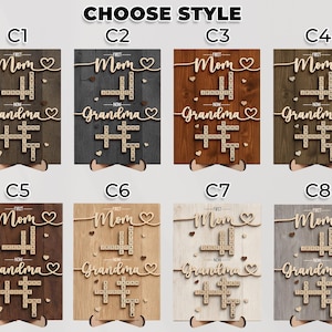 May include: Wooden wall art with the words "First Mom" and "Now Grandma" in a cursive font, with names in a crossword puzzle design. The art is available in various wood tones, with the text "CHOOSE STYLE" at the top.